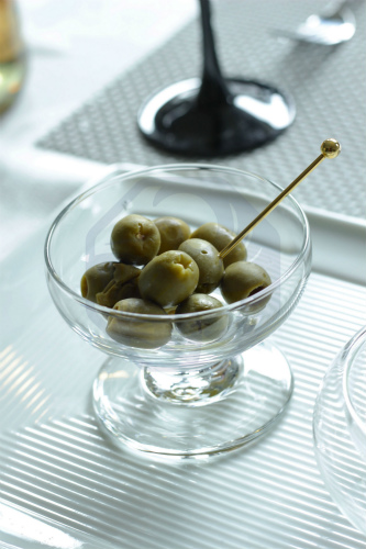 Marinated olives served in a small dish, paired with chilled sake in a traditional sake cup