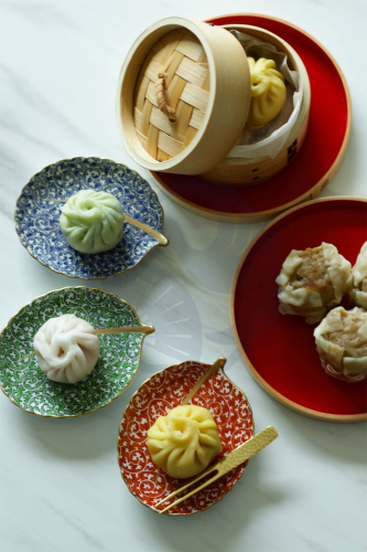 A selection of Chinese dim sum, such as steamed buns and dumplings, paired with Japanese sake.